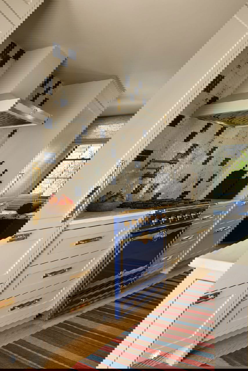 Кухня с ярко-синей плитой в классическом корпусе, белыми шкафами и фартуком из дельфтских изразцов с синими морскими мотивами.