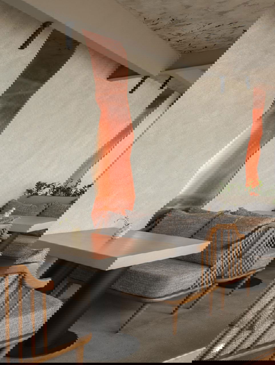 Деталь интерьера: светлые диваны и деревянные кресла у стены с декоративными медными вставками, фактурная штукатурка и акценты в тёплых тонах.