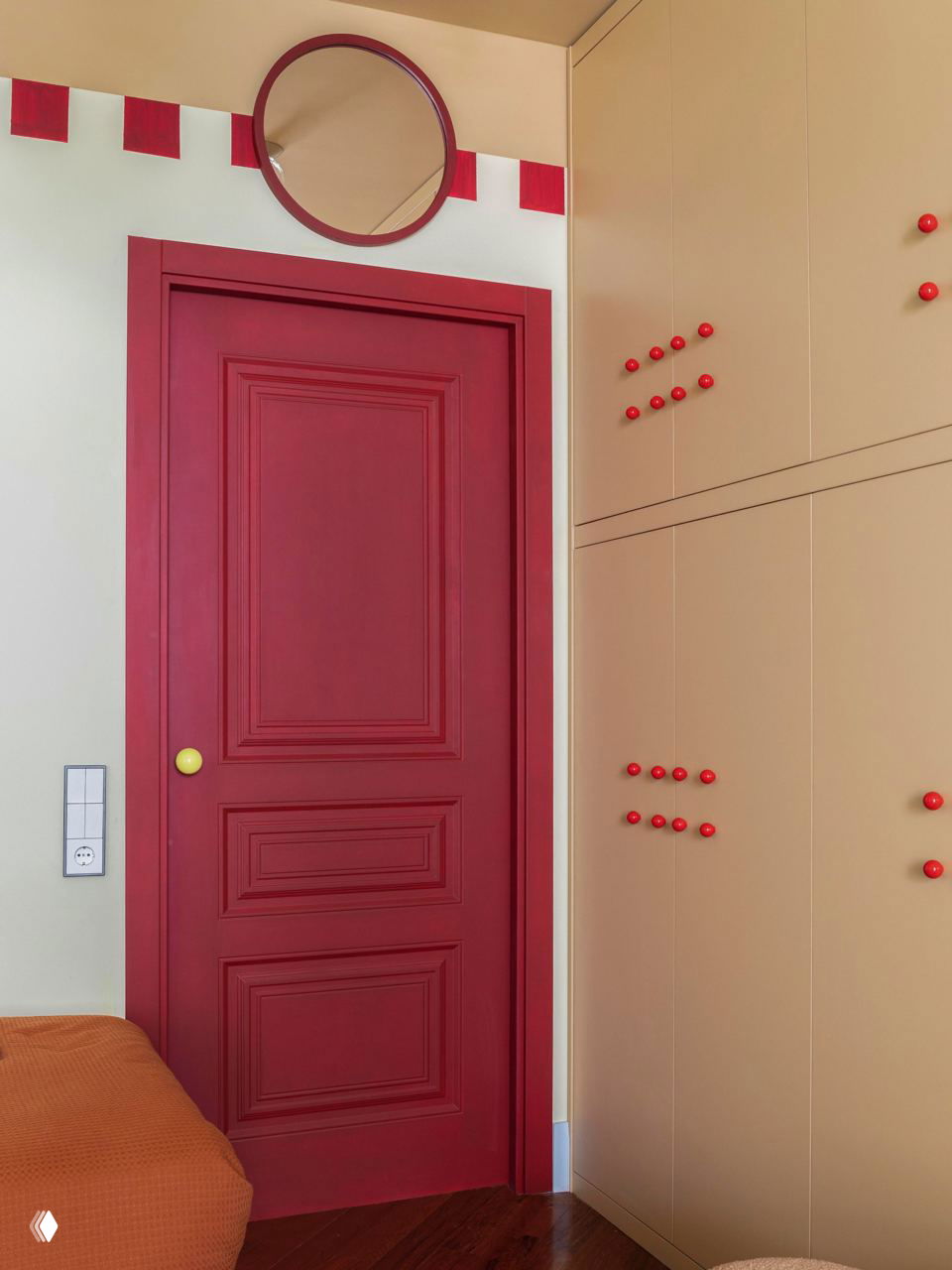Интерьер с бордовой дверью и встроенными шкафами с красными ручками, тёплый деревянный пол и спокойная цветовая гамма — вариант простого обновления двери и фурнитуры.