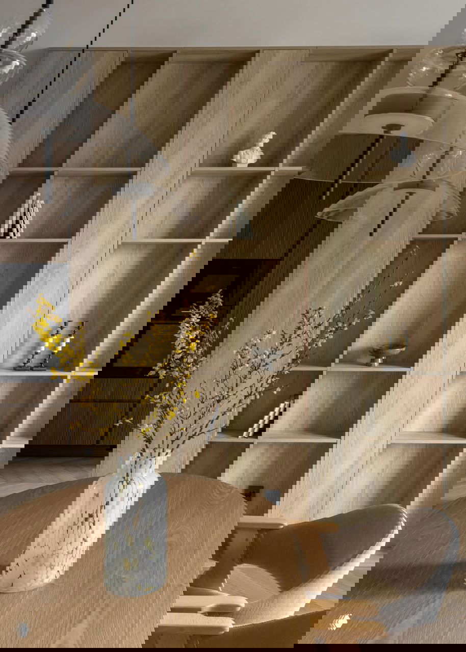 Крупный план деревянных полок и подвесных стеклянных светильников: минималистичные декоративные предметы и вазa на столе в интерьере.