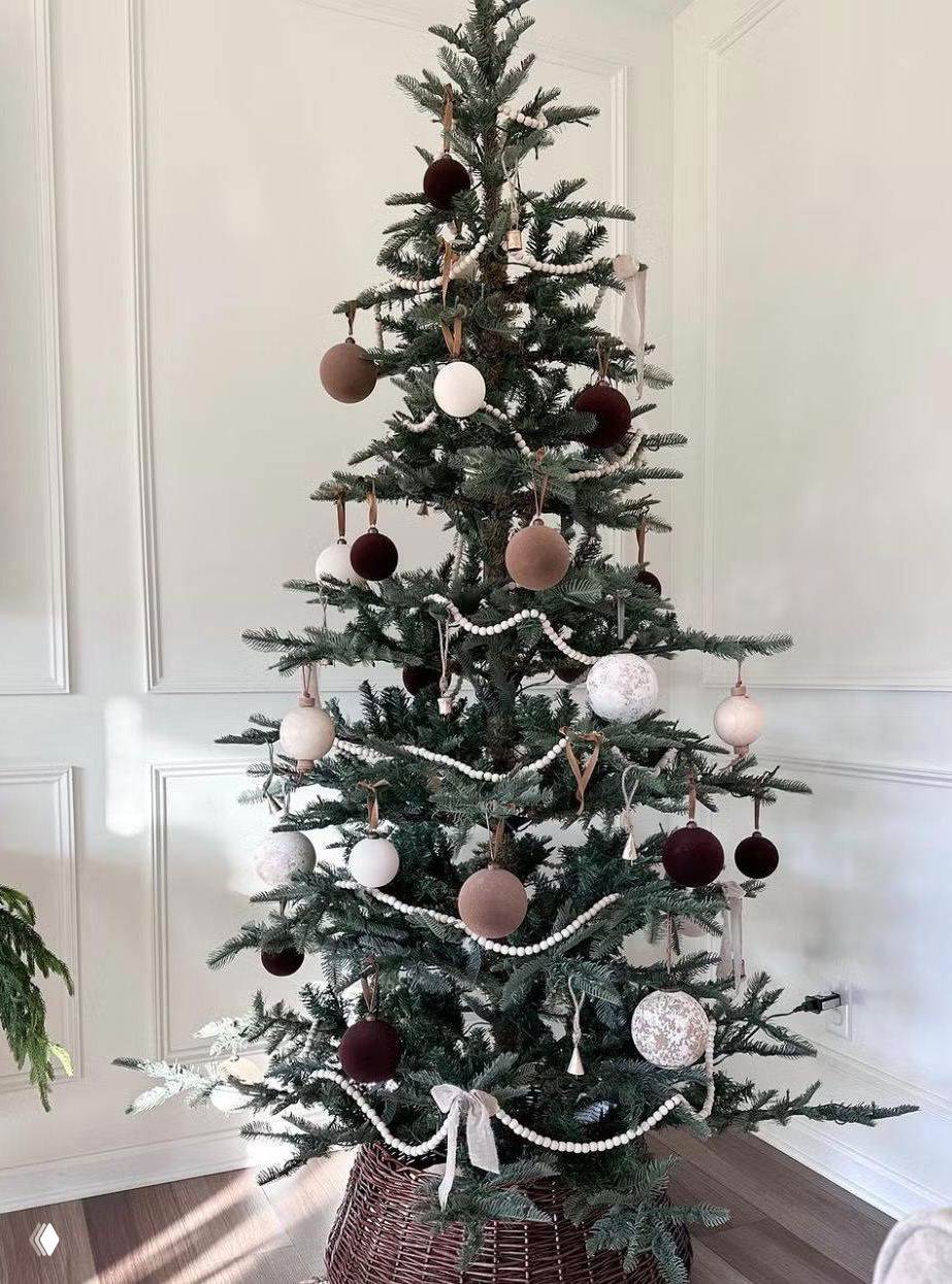 Высокая тонкая ёлка в корзинной подставке: минималистичный интерьер, подвешенные шары и нейтральная цветовая гамма.