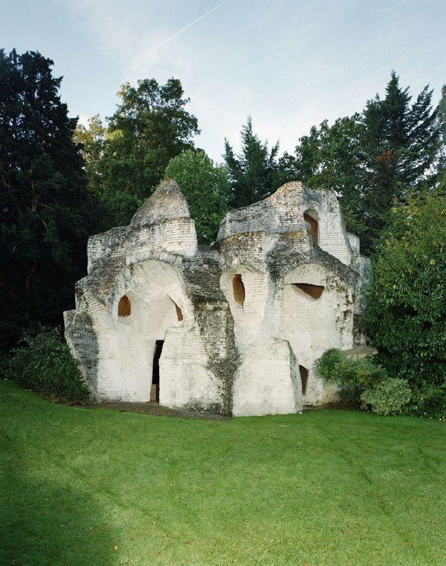 Белая кирпичная «Обитаемая скульптура № 2» Андре Блока на лужайке сада Медона с органическими формами и пещерными нишами в фасаде