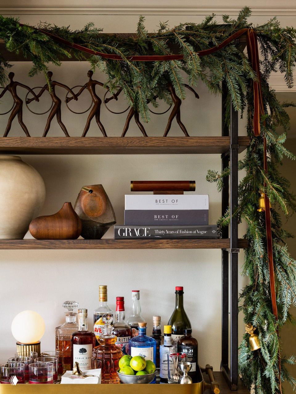 Полка-бар, украшенная хвойной гирляндой и декоративной лентой; сочетание зелёного декора с предметами интерьера в тёплых тонах.