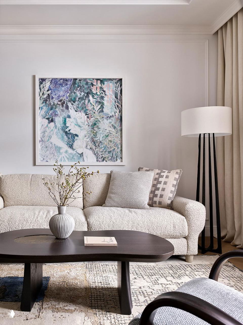 Светлая композиция гостиной с бежевым диваном, текстурным ковром и тёмным деревянным журнальным столом на фоне спокойной пастельной стены с картиной.