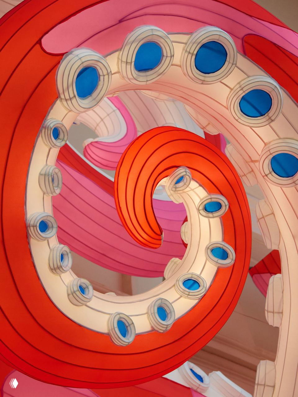 Скульптурный шар с многоцветными улыбающимися «цветами» Мураками и витрины с мини‑сумками Artycapucines на фоне розовых щупалец инсталляции.