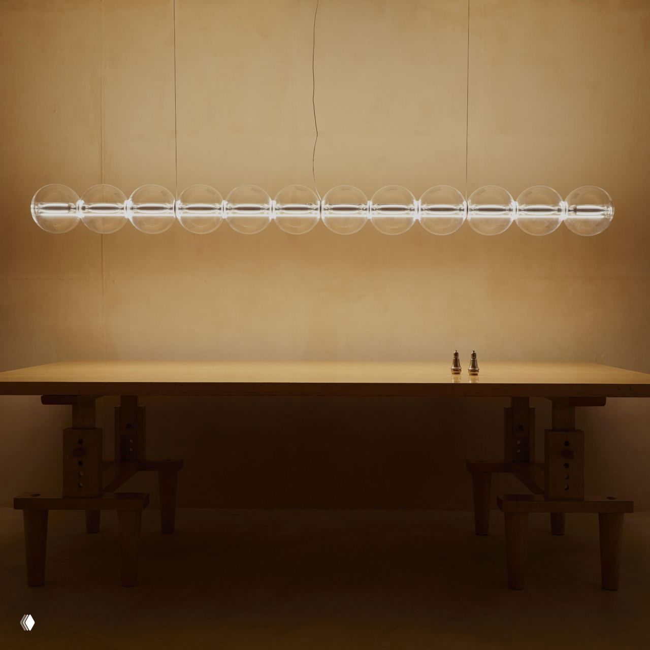 Длинный минималистичный подвесной светильник Flos в пустом пространстве над столом, демонстрация пропорций и модульности версии длиной до нескольких метров.