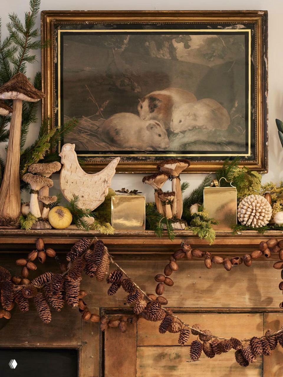 Каминная полка, украшенная натуральными материалами: шишки, гирлянды, фигурки и золотые коробки — природный, тёплый праздничный декор.