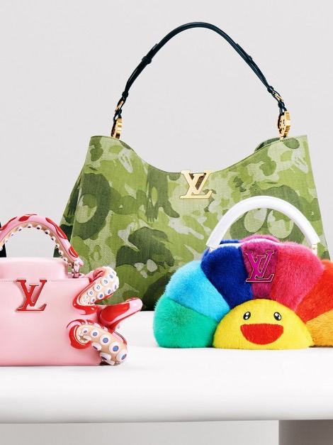 Предметная съемка коллекции Artycapucines: розовая сумка с мини‑осьминогом, камуфляжная сумка и радужная плюшевая деталь на белом столе в экспозиции.