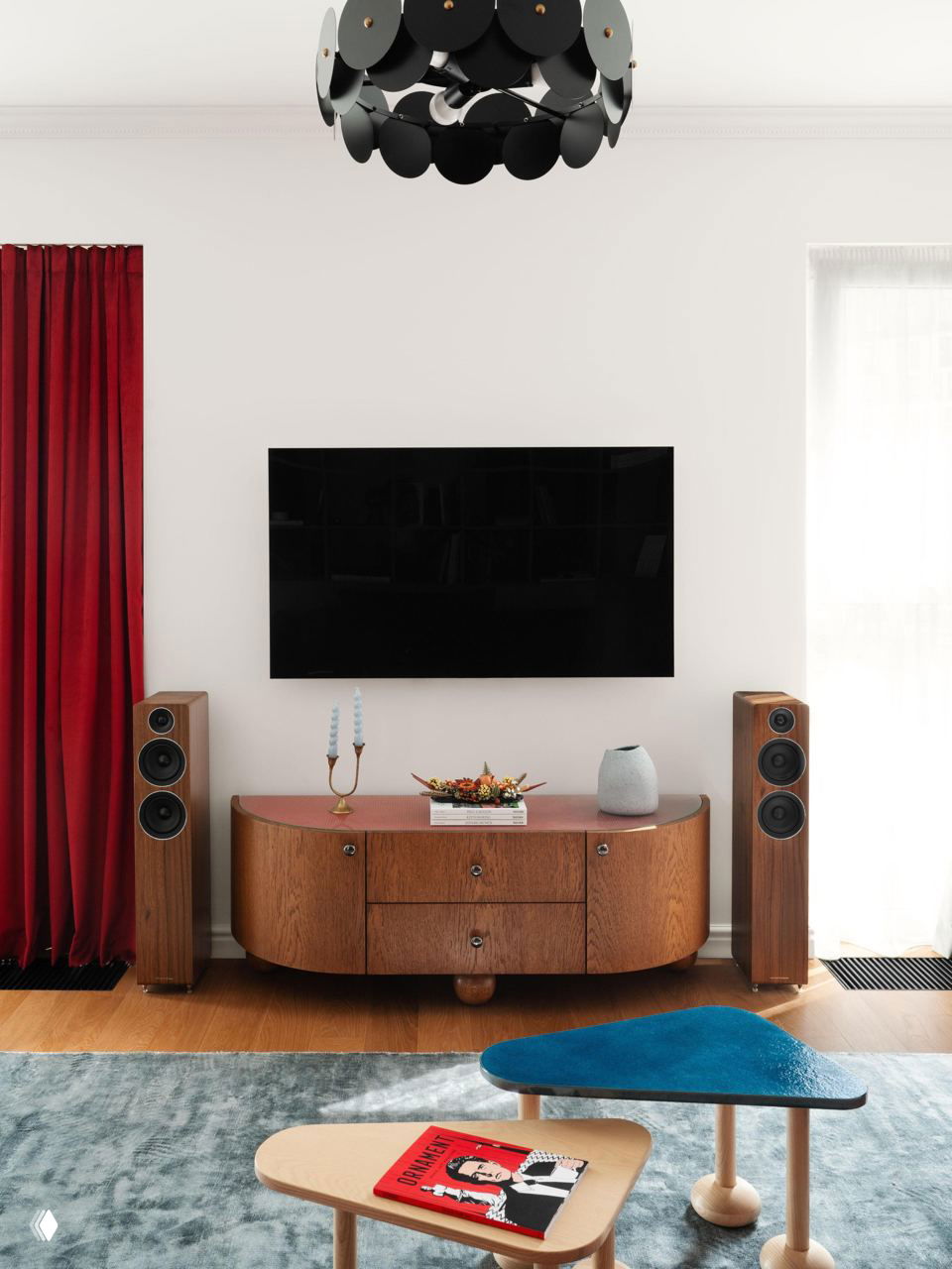 Интерьер с телевизором над тумбой, красные шторы и деревянная тумба в винтажном стиле — сочетание цвета и ретро-акцентов в гостиной.