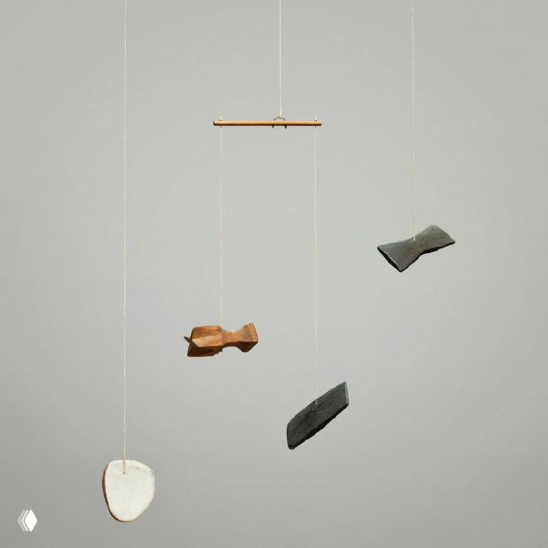 Детальный кадр нескольких маленьких деревянных фигур мобиля Колдера на верёвках: формы, цвет и поверхность материалов хорошо просматриваются крупным планом.