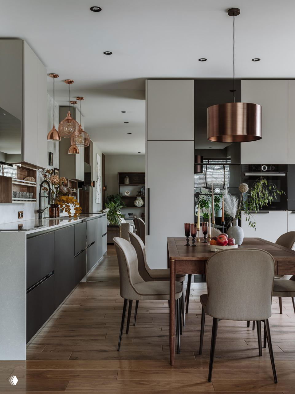Кухня-столовая в проекте: открытая планировка с тёплым деревянным полом, тёмными низкими шкафами, медными подвесными светильниками и обеденным столом.