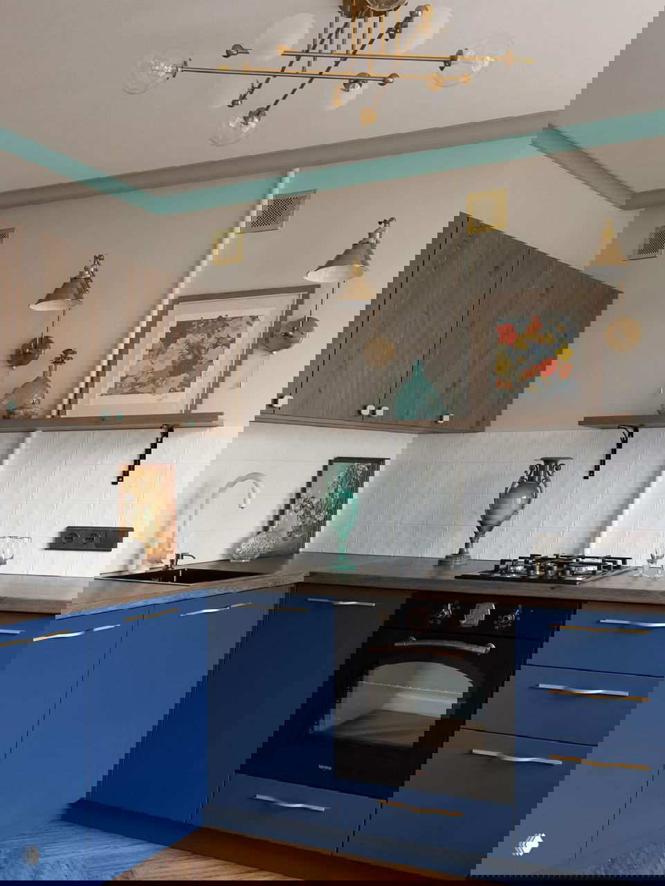 Угловая кухня с глубокими синими фасадами, деревянной столешницей, мятной окантовкой потолка и винтажными аксессуарами в интерьере.