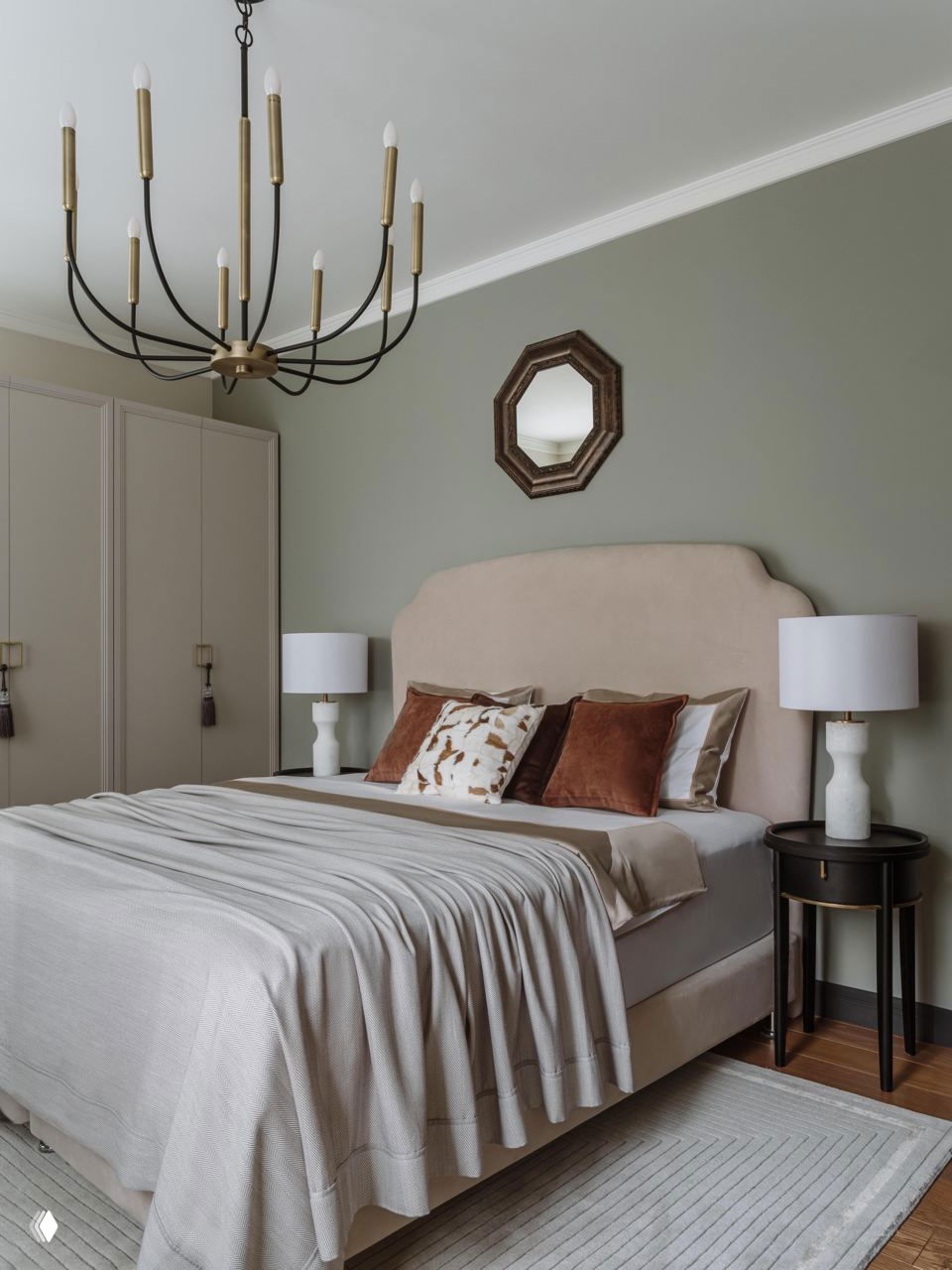 Спальня в современной классике: мягкое изголовье бежевого тона, приглушённые зелёные стены, подвесная люстра и спокойная текстильная гамма.