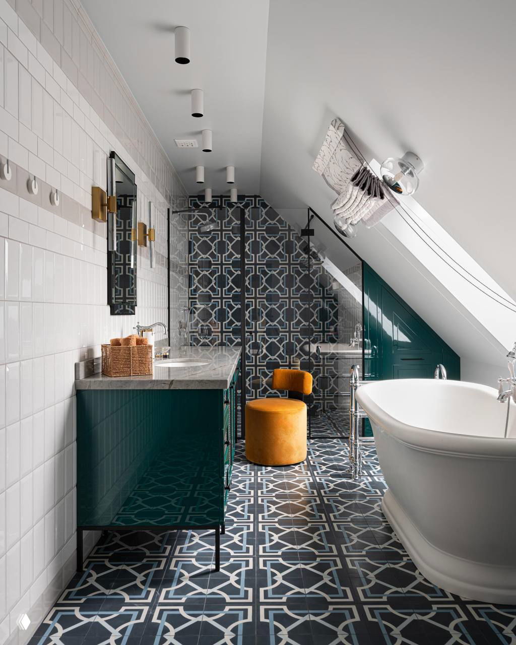 Ванная под мансардой: свободностоящая ванна, темно-синие узорные плитки, зелёные тумбы и яркий бархатный пуф — контрастная и уютная композиция.