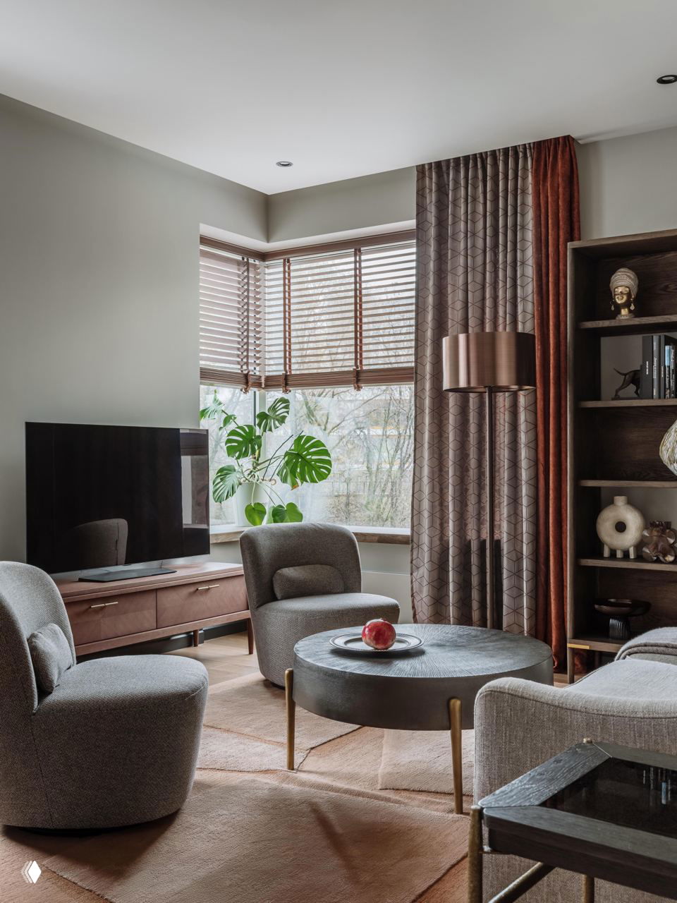 Уютная гостиная зона с низкими креслами и круглым журнальным столиком, большое окно с видом на реку и зелёный пейзаж за окном.