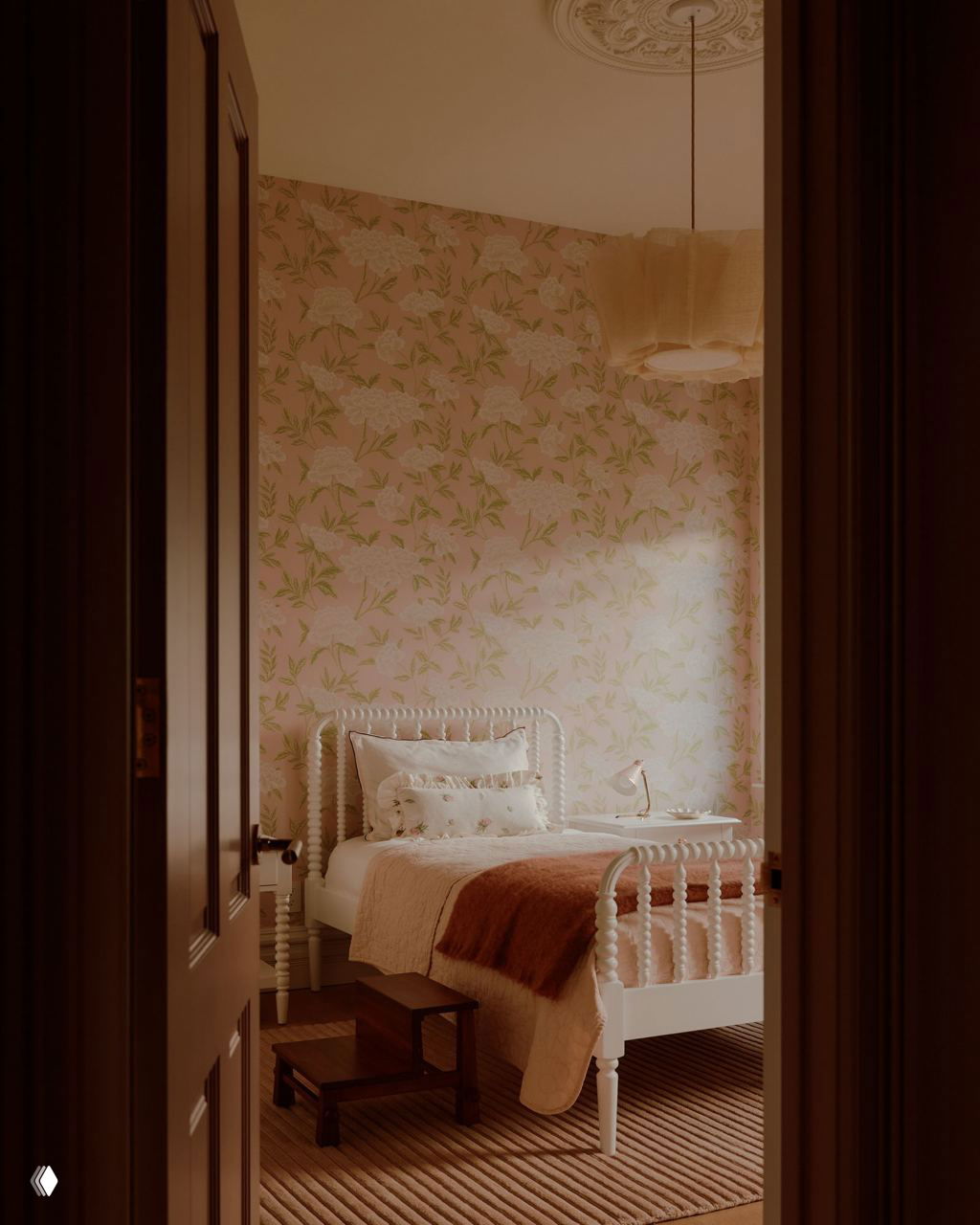 Нежная спальня с белой резной кроватью, цветочными обоями и спокойной палитрой — сочетание английской романтики и калифорнийского уюта.