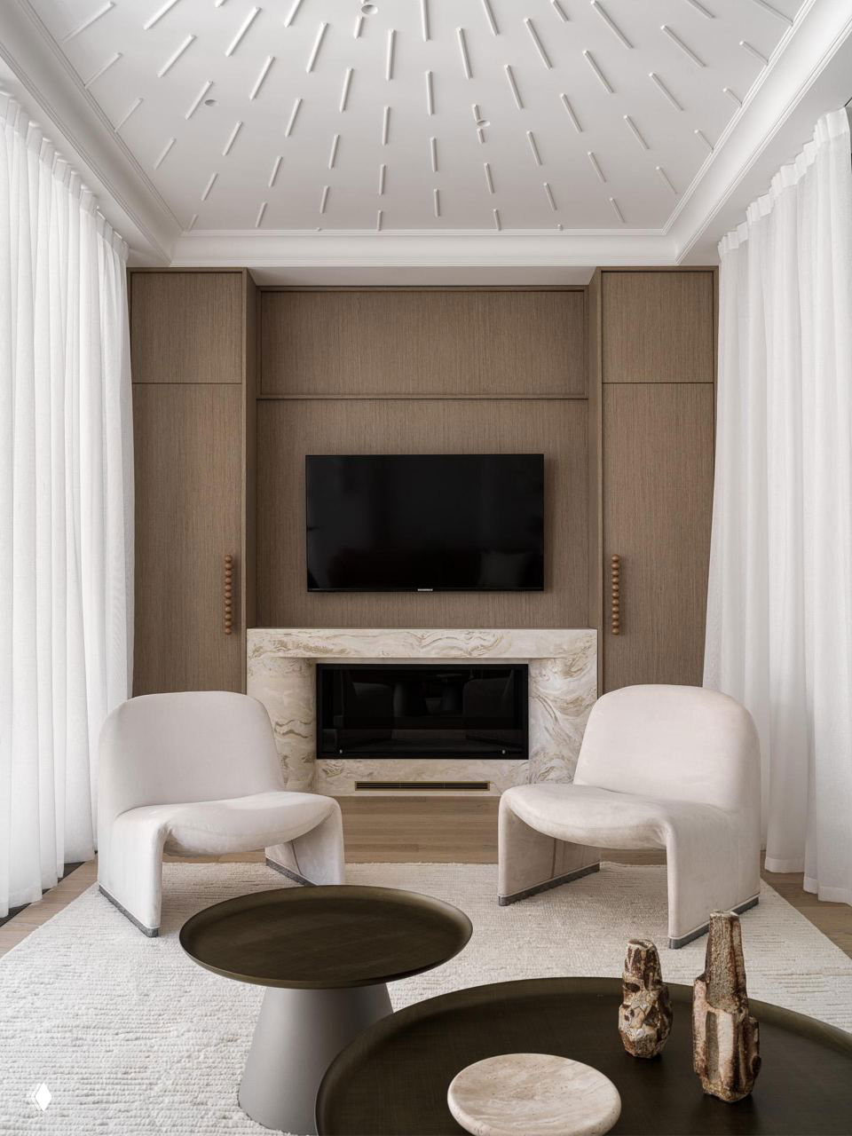 Минималистичная гостиная с двумя скульптурными мягкими креслами и мраморным камином — пример театральной пластики мебели и лаконичной отделки.