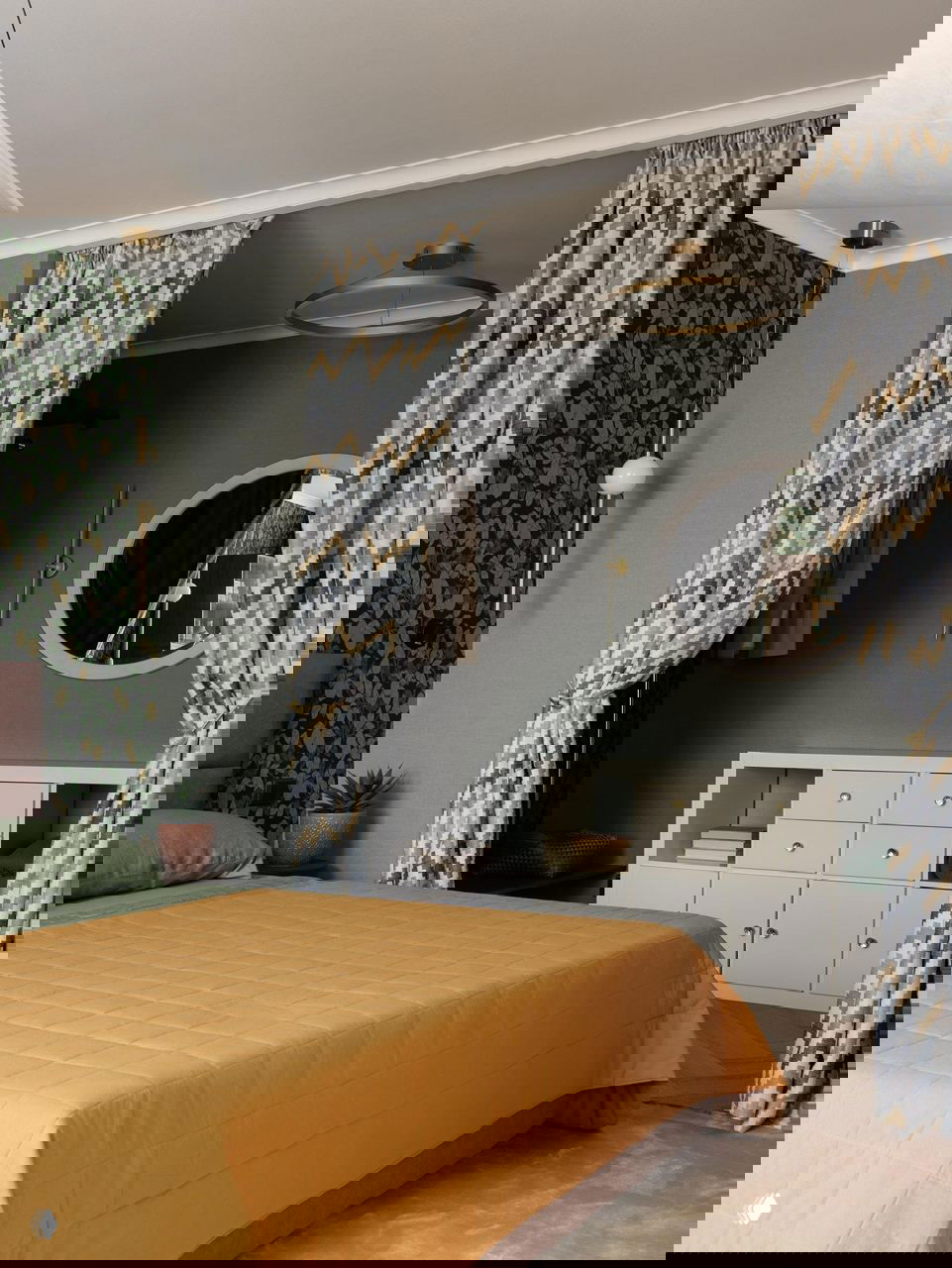 Спальня с горчичным покрывалом, зелеными подушками и гардеробной нишей за текстильными шторами — сочетание цветов и фактур в интерьере.