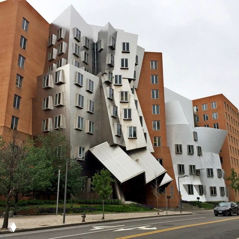 Фрагмент фасада с волноподобными металлическими поверхностями и небольшими окнами, пример деконструктивистской архитектуры Фрэнка Гери.