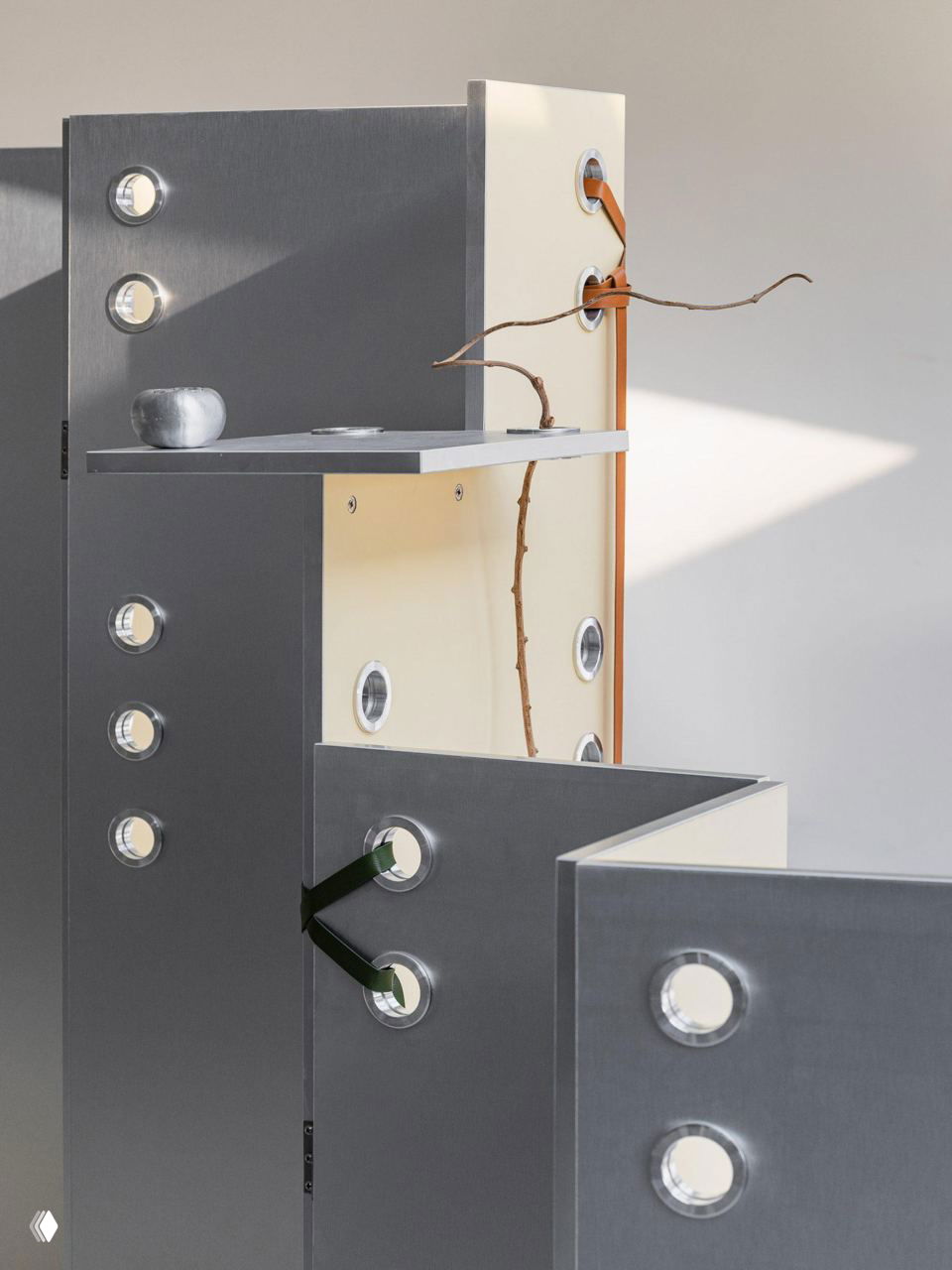 Крупный план угловых панелей и перегородок с круглыми окнами и кожаными элементами, часть композиции напоминает заострённые листы и стебли растений.