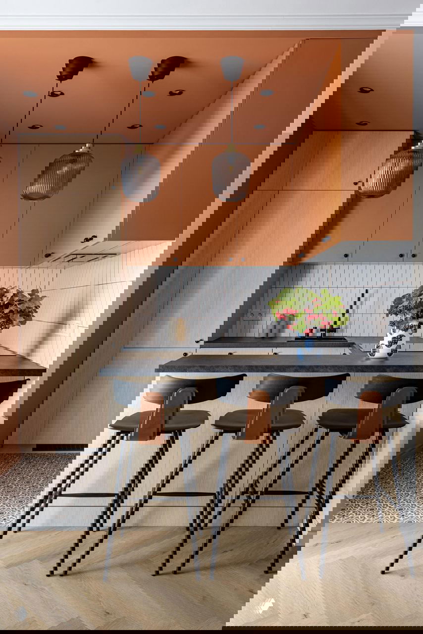 Кухня с терракотовым цветом потолка и шкафов, барная стойка с тремя стульями и подвесными светильниками; контрастная и функциональная зона.