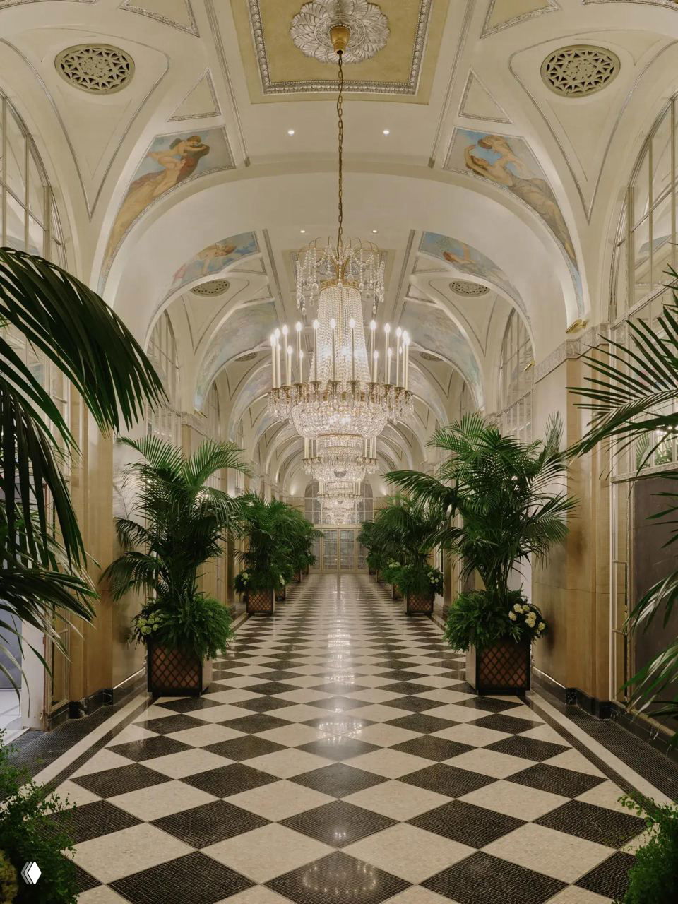 Длинный Серебряный коридор отеля с мраморным шахматным полом, пальмами в кадках и крупными хрустальными люстрами под сводчатым потолком.