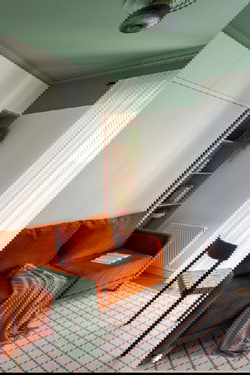 Комната с зелёным потолком и бархатным терракотовым диваном, сочетание спокойных тонов и ярких акцентов, мягкий текстиль и дневное освещение.