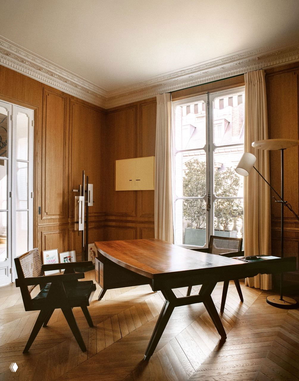 Столовая с большими окнами и деревянными панелями: лакированный стол, кресла Джо Понти и мягкая дневная освещённость в классическом парижском интерьере.