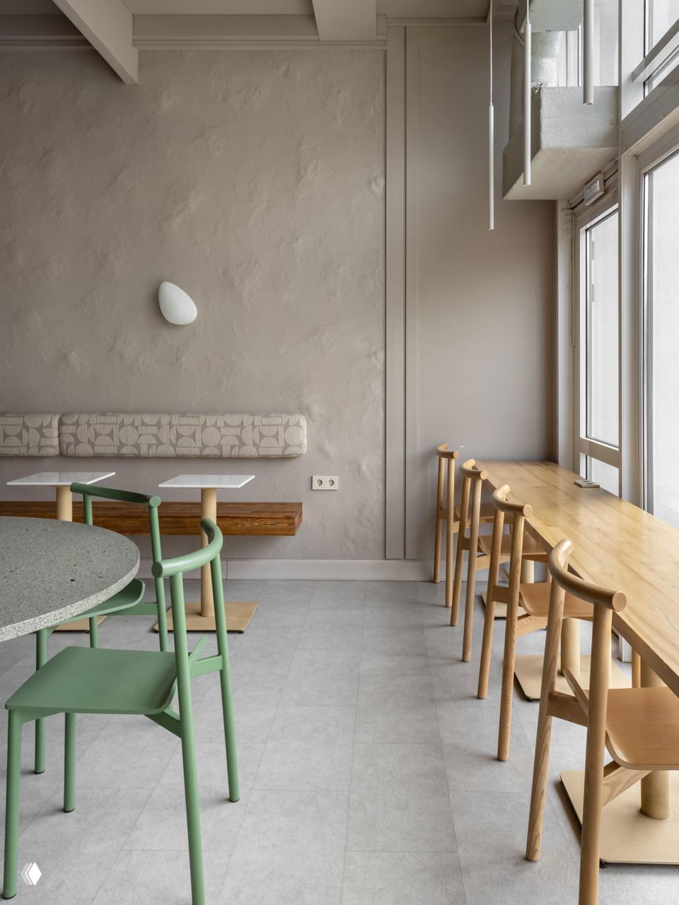 Угловая зона с барной стойкой у окна: деревянная столешница, ряд высоких табуретов и светлый пол в спокойной джапанди-палитре.