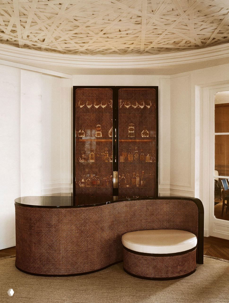 Барная стойка с округлыми формами и витриной из тёмного дерева: свечения стекла, плетёная текстура и мягкие линии в переходном пространстве квартиры.