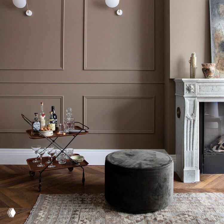 Интерьер с элегантным камином, маленьким барным столиком и бархатным пуфом на паркетном полу: сдержанная нейтральная палитра и теплая атмосфера