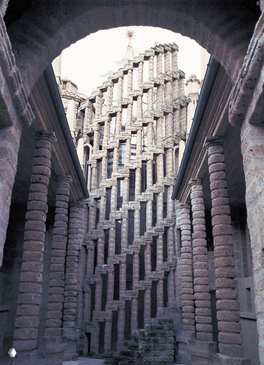 Внутренний вид Ла Скарцуола: высокие колонны и ступенчатая башня из пористого туфа, архитектурный приём напоминает лестничные структуры.