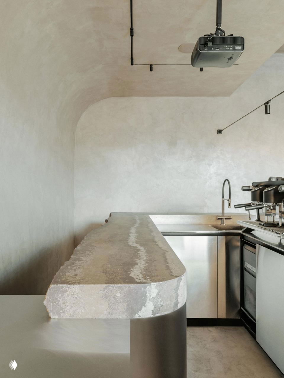 Деталь барной стойки: фактура разрушенного бетона сверху и блестящая нержавеющая сталь снизу, акцент на материалах и формах.