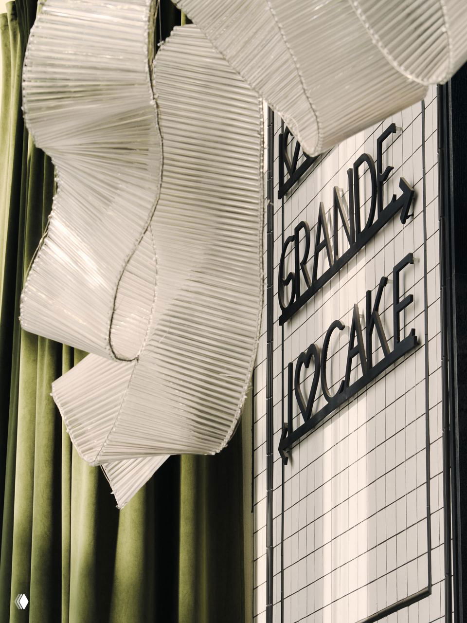 Крупный план декоративного оформления стены и вывески Grande с текстильными драпировками и крупными художественными элементами интерьера.