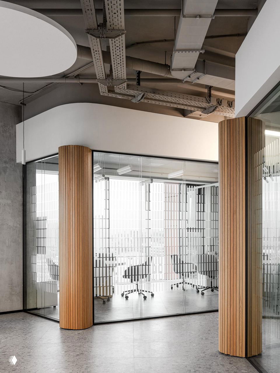 Переговорная с прозрачными стенами, деревянные колонны, офисные кресла на колесиках, светлый пол и индустриальный потолок в офисе 2ГИС в Москве.