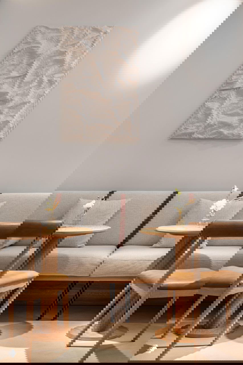 Минималистичный уголок ресторана Savras: светлый диван, ремни в декоре и круглые деревянные столики для небольших посиделок в стиле high tea.