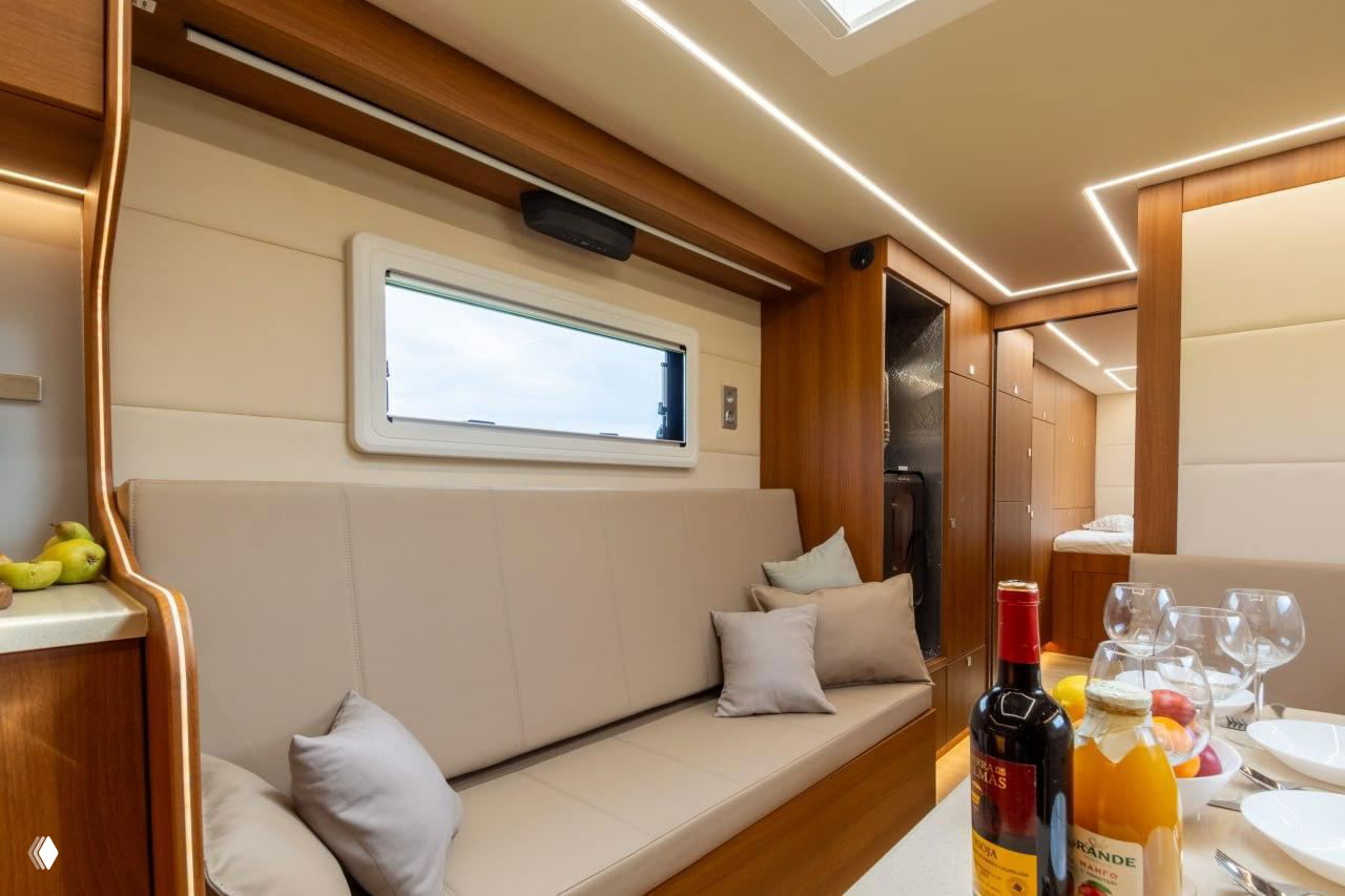 Диванная зона внутри жилого модуля: мягкие подушки, окно в боковой стене и продуманная LED-подсветка потолка и шкафов, современный интерьер.