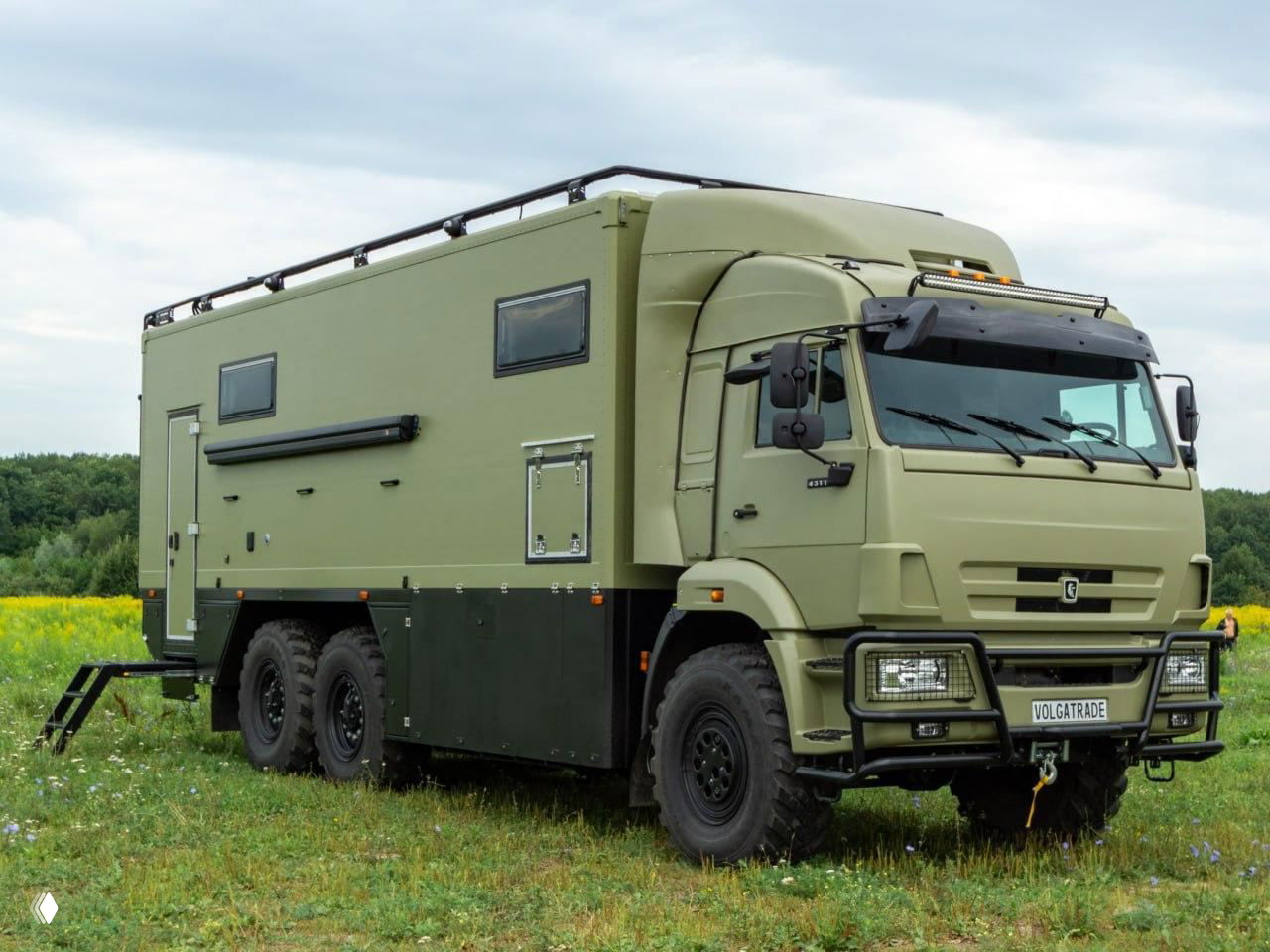 Шестиколесный зелёный КамАЗ-43118 с жилым модулем на бездорожье, крупный план кабины и вместительного модуля автодома, внешний вид.
