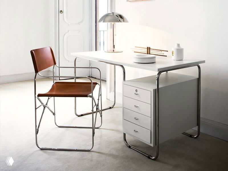 Светлая рабочая зона с белым столом в металлокаркасе и кожаным стулом — фотография показывает утилитарный ретро-дизайн и исполнение предмета мебели.