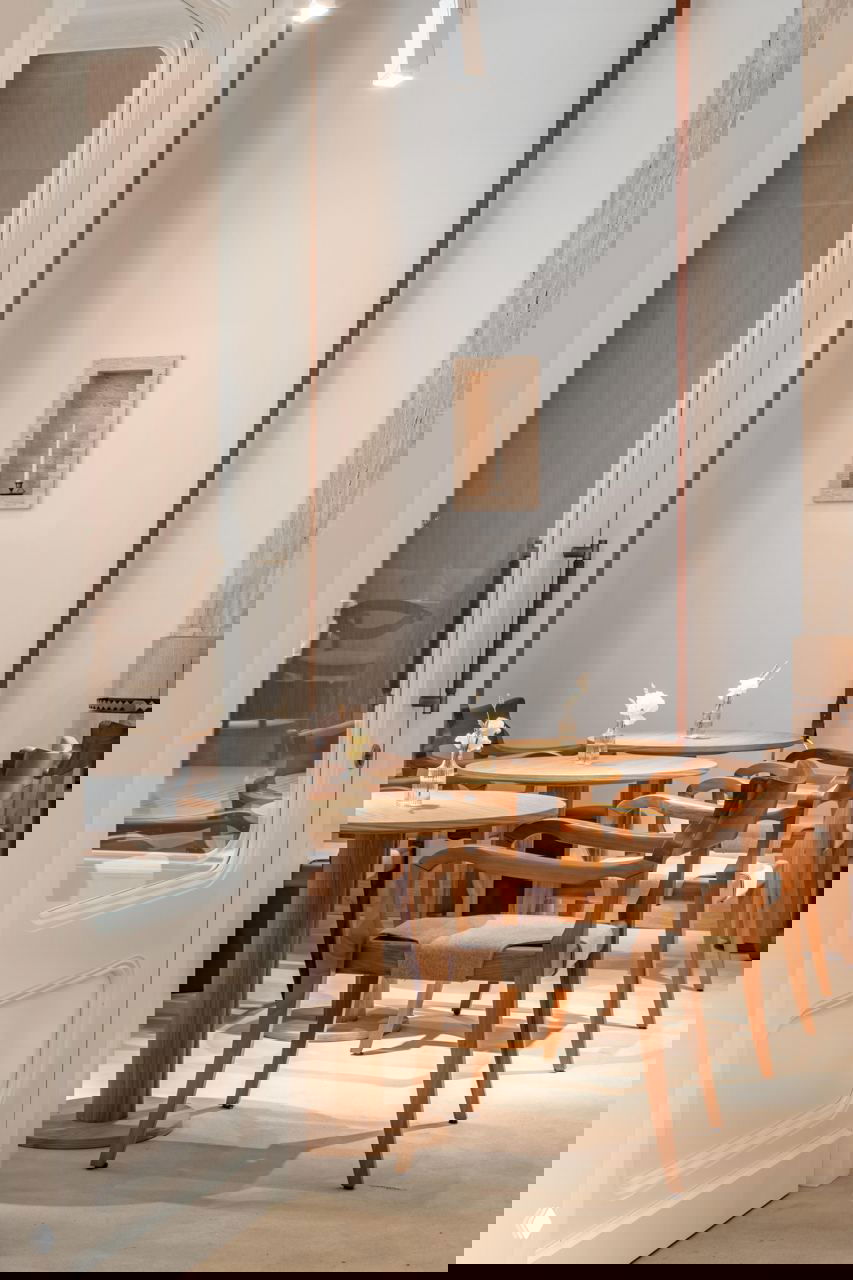 Узкий светлый зал с круглыми деревянными столами и стульями, белыми стенами и высоким потолком — атмосферное продолжение французской темы в Savras.