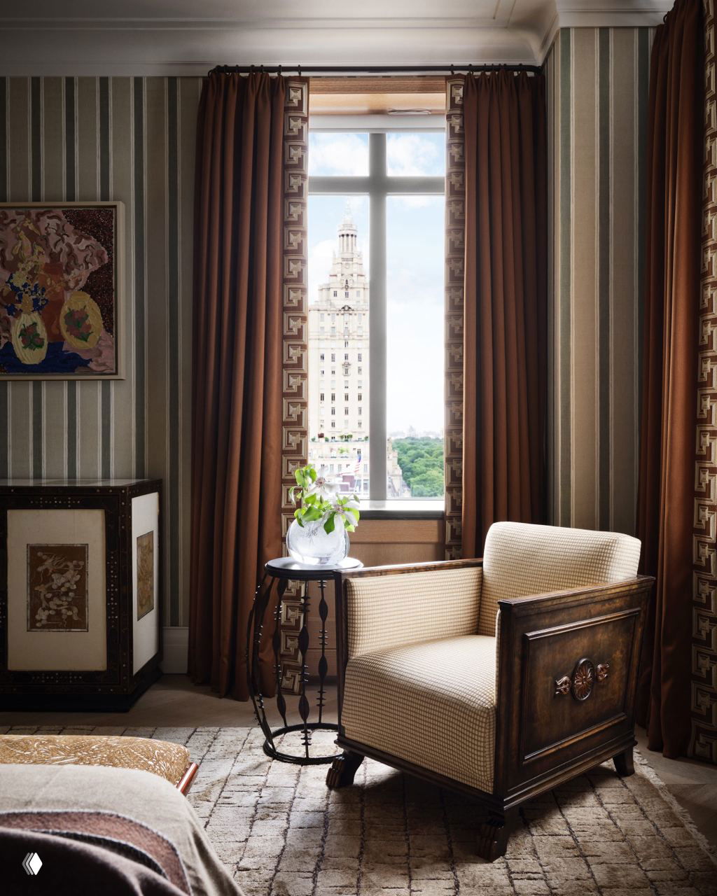 Уютное кресло у окна в ар‑деко интерьере: плотные шторы, узорчатые обои и вид на историческое здание и зелёные массивы парка за окном.