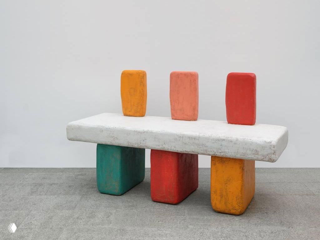 Скамья или табурет с разноцветными опорами и белой верхней панелью, объекты с насыщенной матовой краской и фактурой, оформленные как арт-объекты.