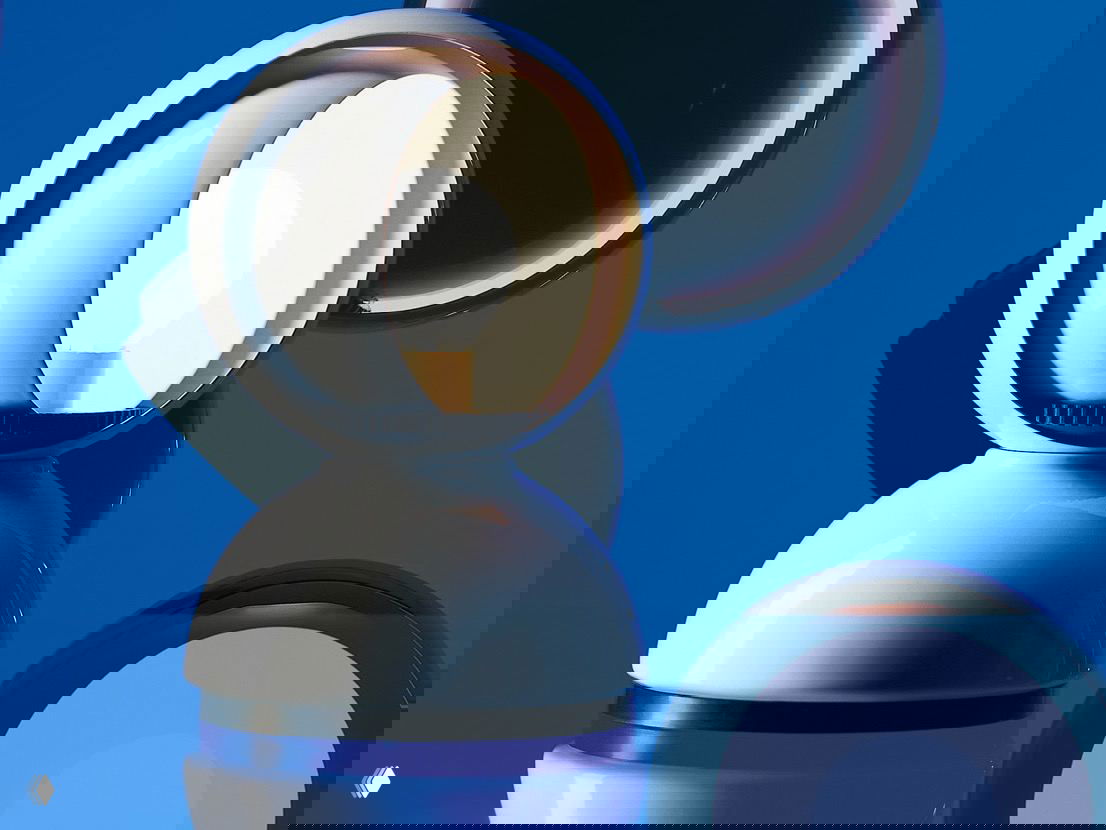 Крупный план коллекционного осветительного предмета: белая сферическая лампа с открытой чашей на фоне насыщенного синего фона, акцент на форме и отражениях.