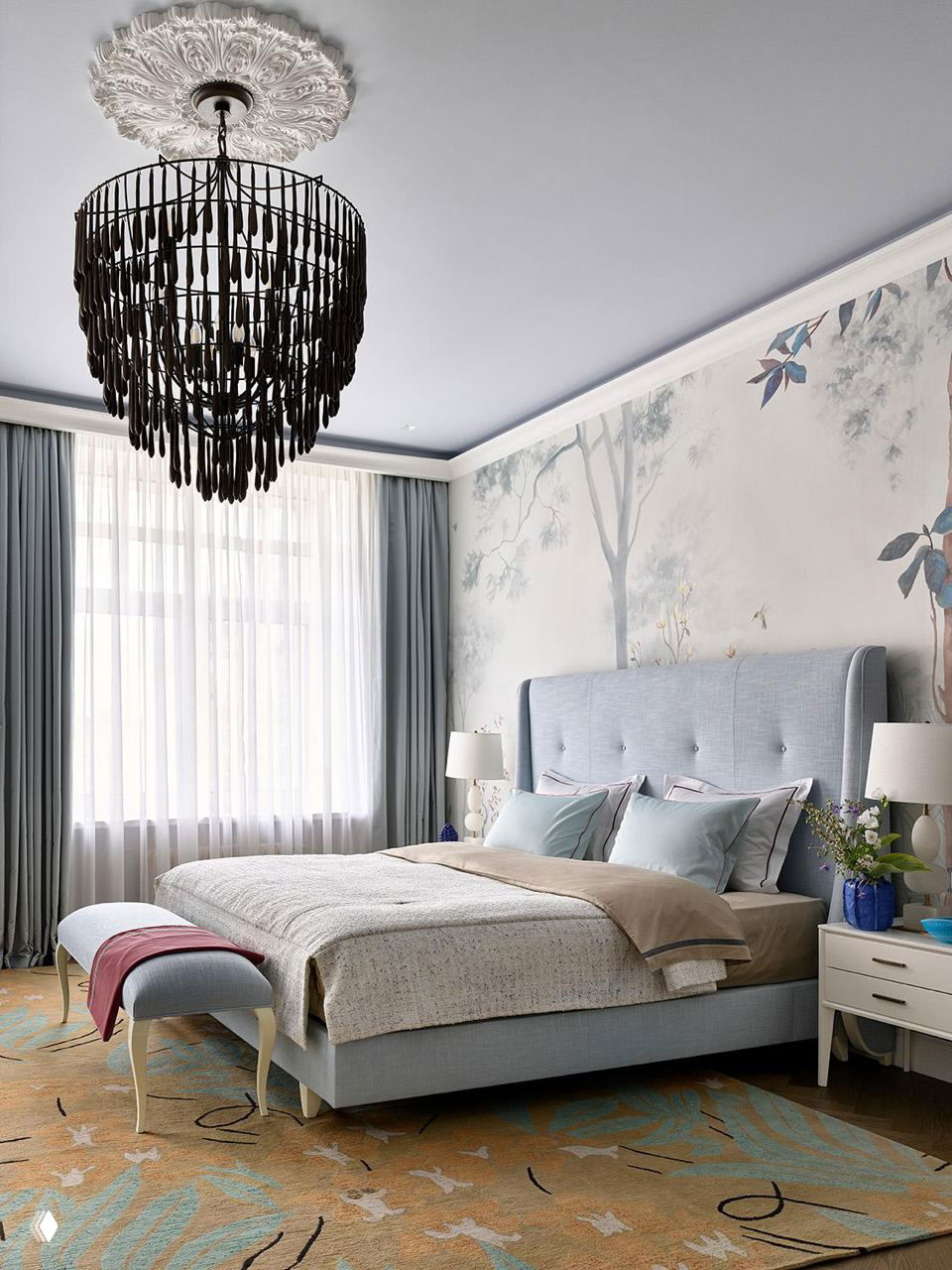 Спальня с мягким голубым изголовьем, декоративной фреской на стене, крупной тёмной подвесной люстрой и текстильными слоями в спокойных серо-голубых тонах.