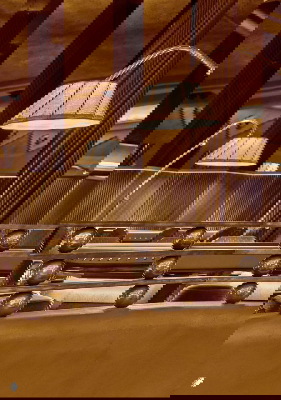 Деталь интерьера: настольные лампы, зеркальные колонны и декоративная балюстрада в тёплой охристой палитре.