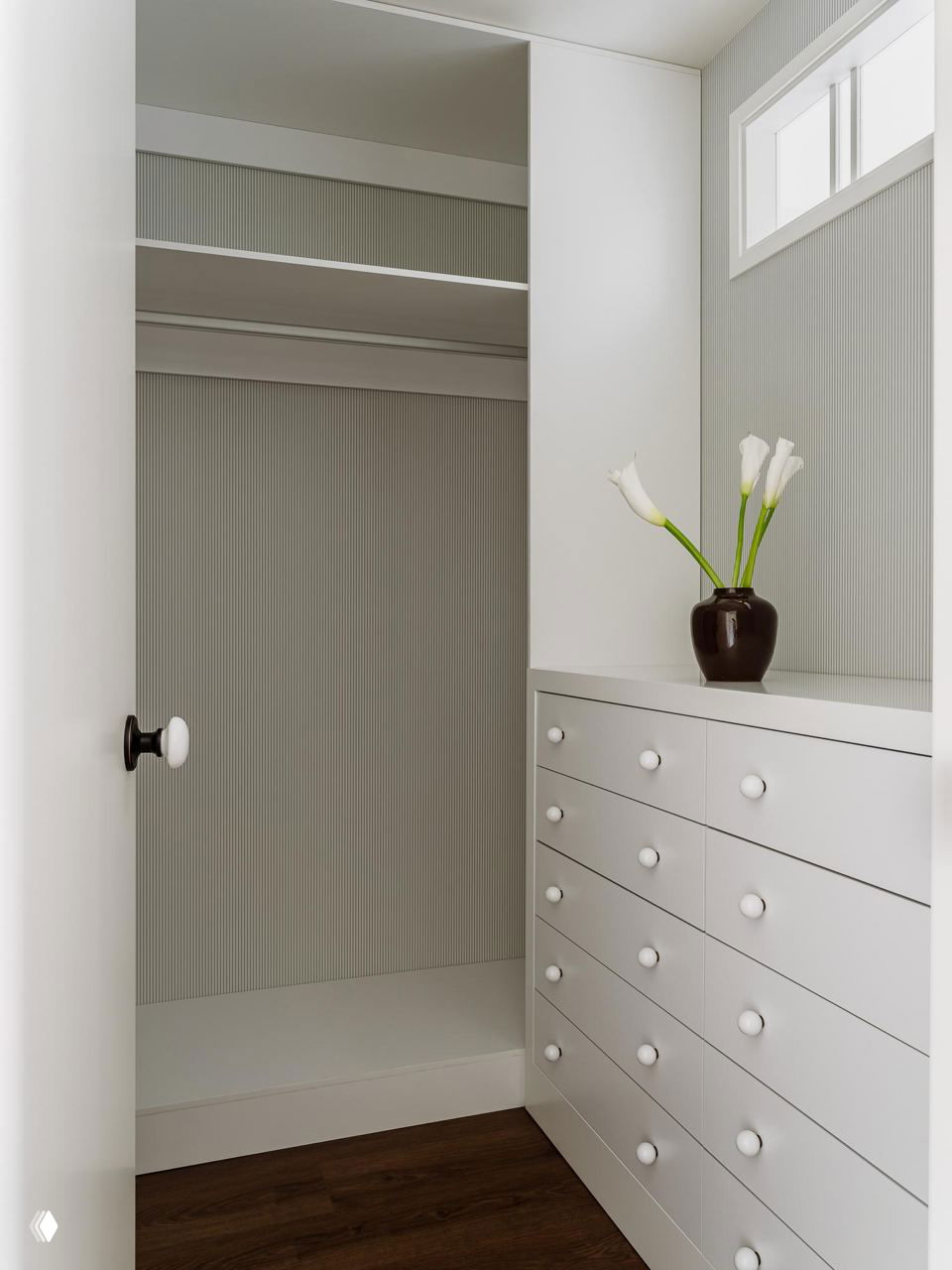 Гардеробная ниша с белыми выдвижными ящиками и вертикальной рифлёной отделкой стен — компактная и светлая зона для хранения вещей в квартире.