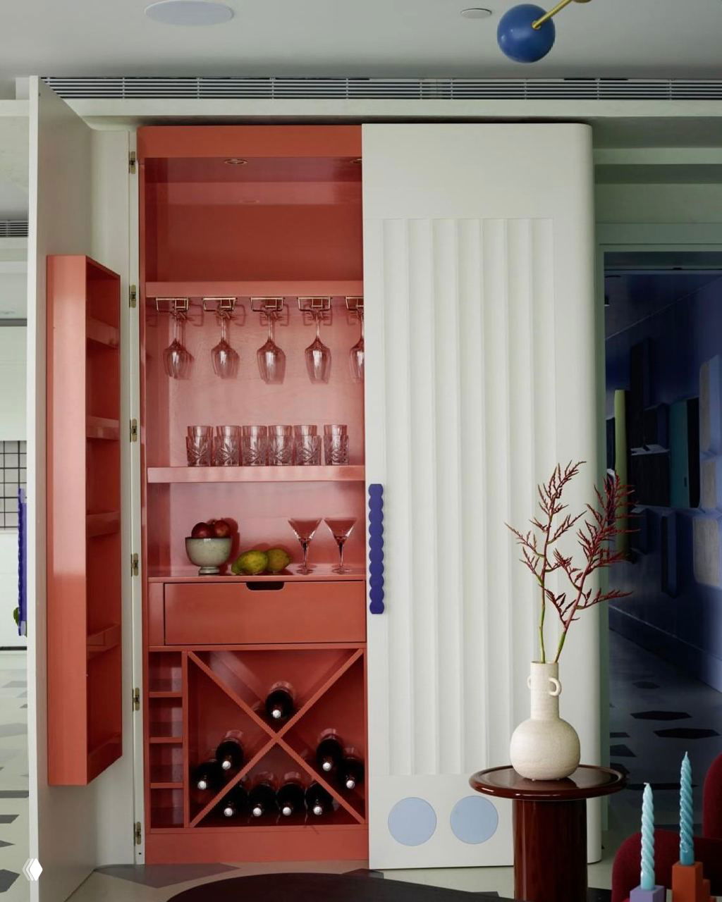 Открытая внутренняя ниша-пенал с коралловым интерьером: полки, стойка для бокалов и секции для вина, демонстрирующие идею скрытых кладовых.