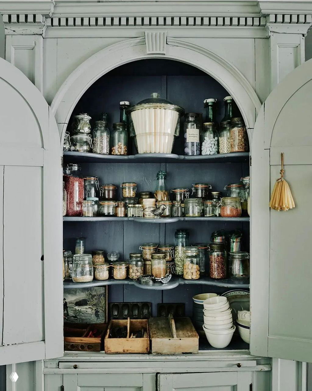 Старинный шкаф-кладовая с арочной нишей, наполненный банками и сухими продуктами — пример организованного хранения в классическом стиле.
