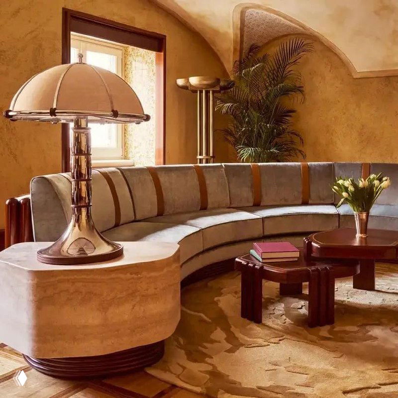 Интерьер с бархатным диваном и скульптурным журнальным столом в тёплой гамме; гламурные декоративные акценты и зеркальные поверхности в кадре.