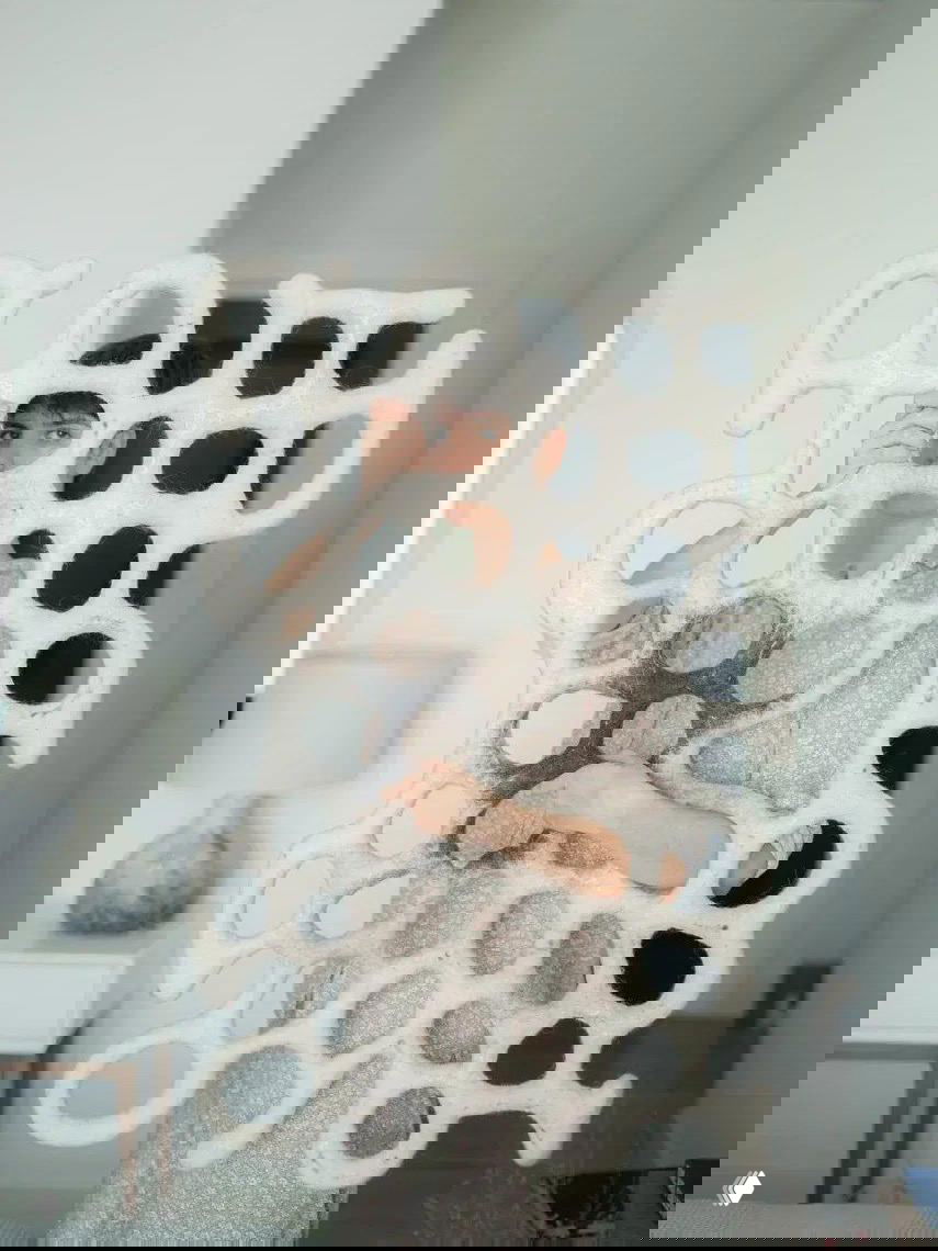 Алена Селезнева держит крупную белую войлочную панель с органическими отверстиями на фоне светлого интерьера, демонстрируя форму и текстуру.